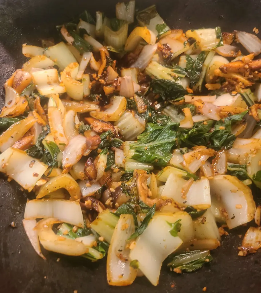 Stir fried onions and shiitake mushroom, now accompanied by steamed bok choy leaves, ready to be combined with the protein for this meal.